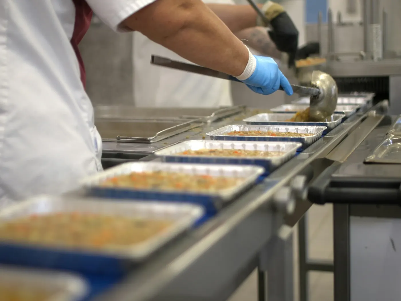 A worker filling meal trays on a conveyor